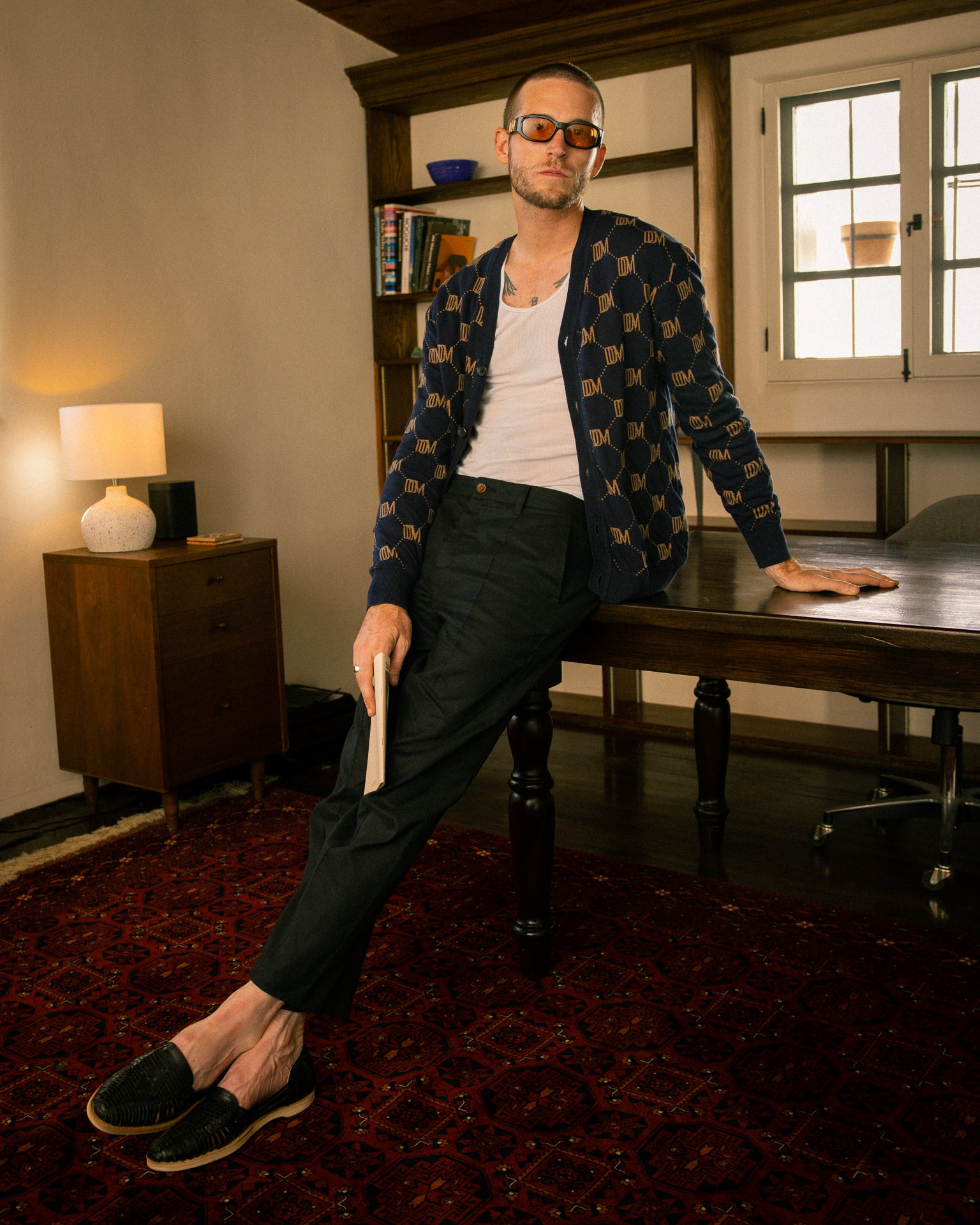 A man sitting on a desk holding The Castello Cardigan - Abyss by Dandy Del Mar.