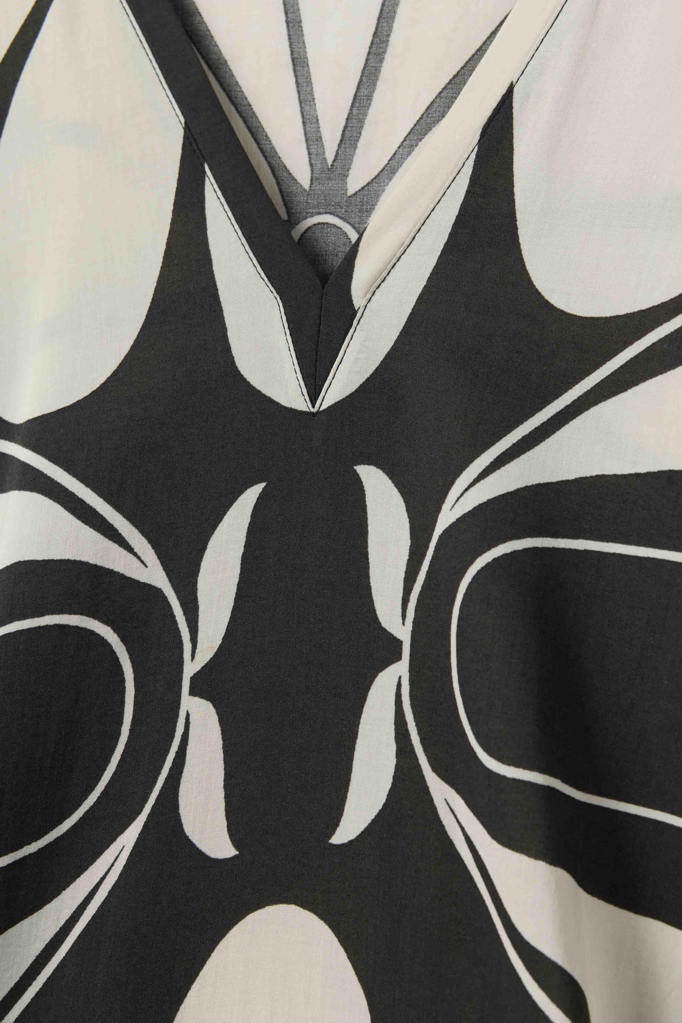 Close-up of The Tropea Kaftan - Albatross by Dandy Del Mar, featuring a bold black and white abstract pattern and V-shaped neckline—ideal for stylish beachwear.