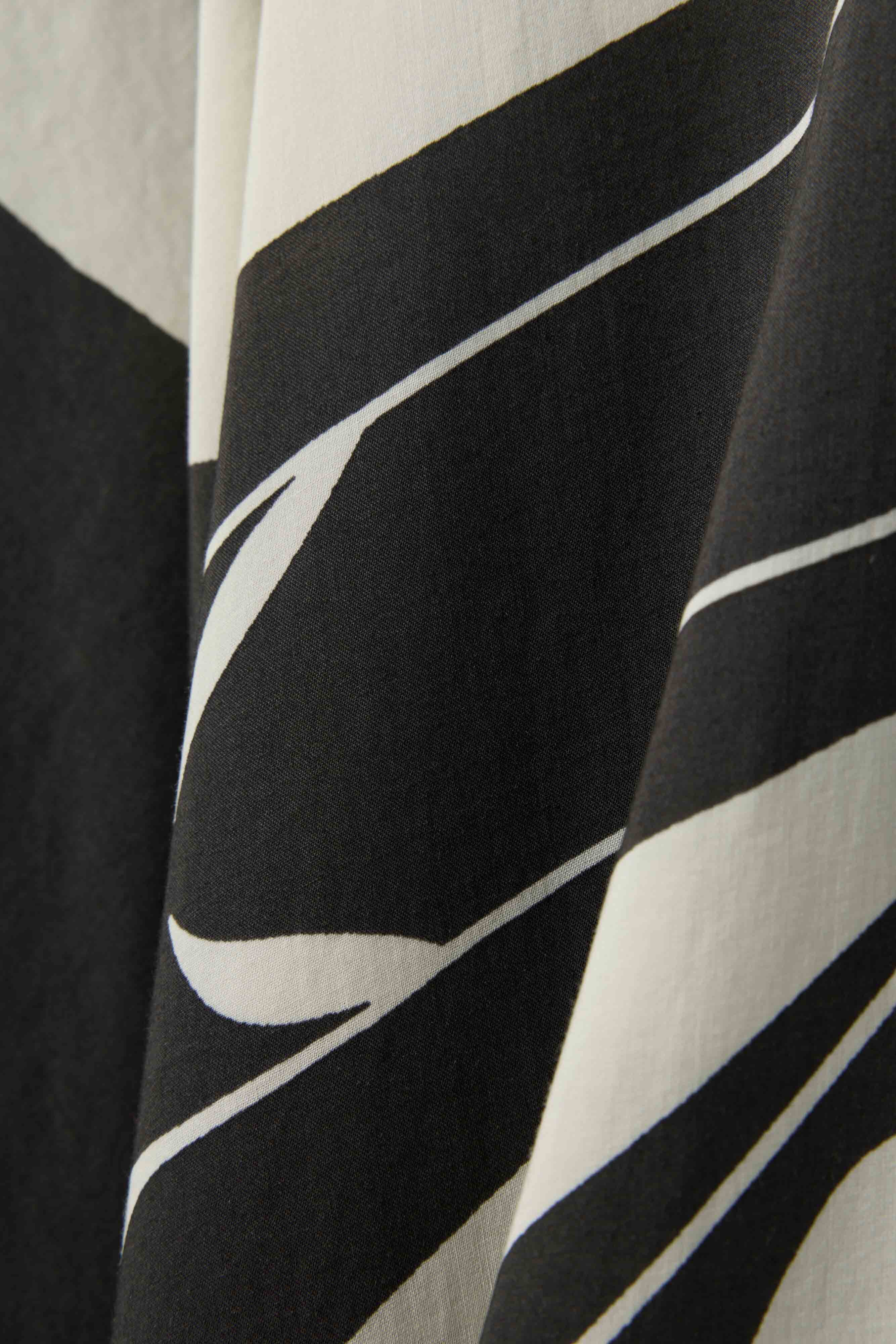 Close-up of The Tropea Kaftan - Albatross by Dandy Del Mar in black and white with bold, abstract curves. Its soft fabric drapes beautifully, making it the perfect elegant kaftan for stylish beachwear.