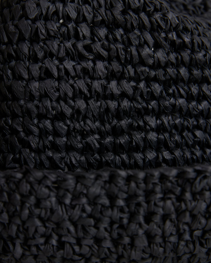 Close-up view of a textured black fabric with a detailed raffia-effect crochet pattern on The Amabile Raffia Hat in Onyx by Dandy Del Mar.