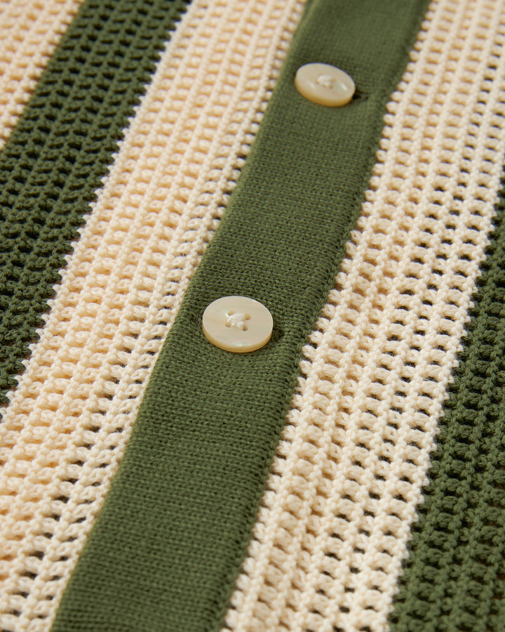 A close up of an elegant Dominica Crochet Shirt - Arbequina, by Dandy Del Mar, in green and white, combining comfort and style.
