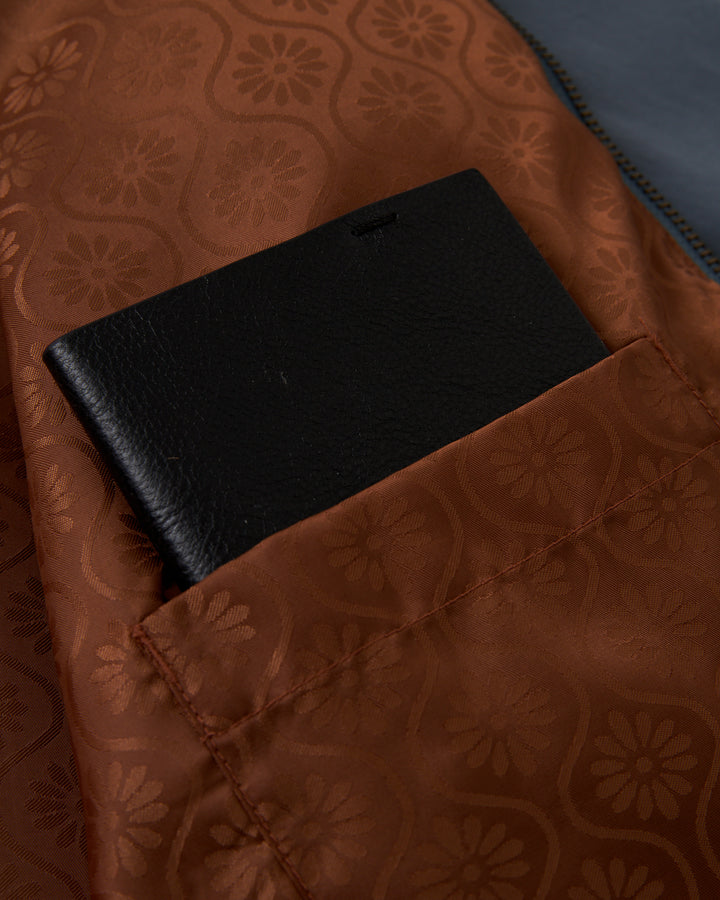 The pocket of a Dandy Del Mar Rhodes Jacket - Abyss has a black wallet in it.
