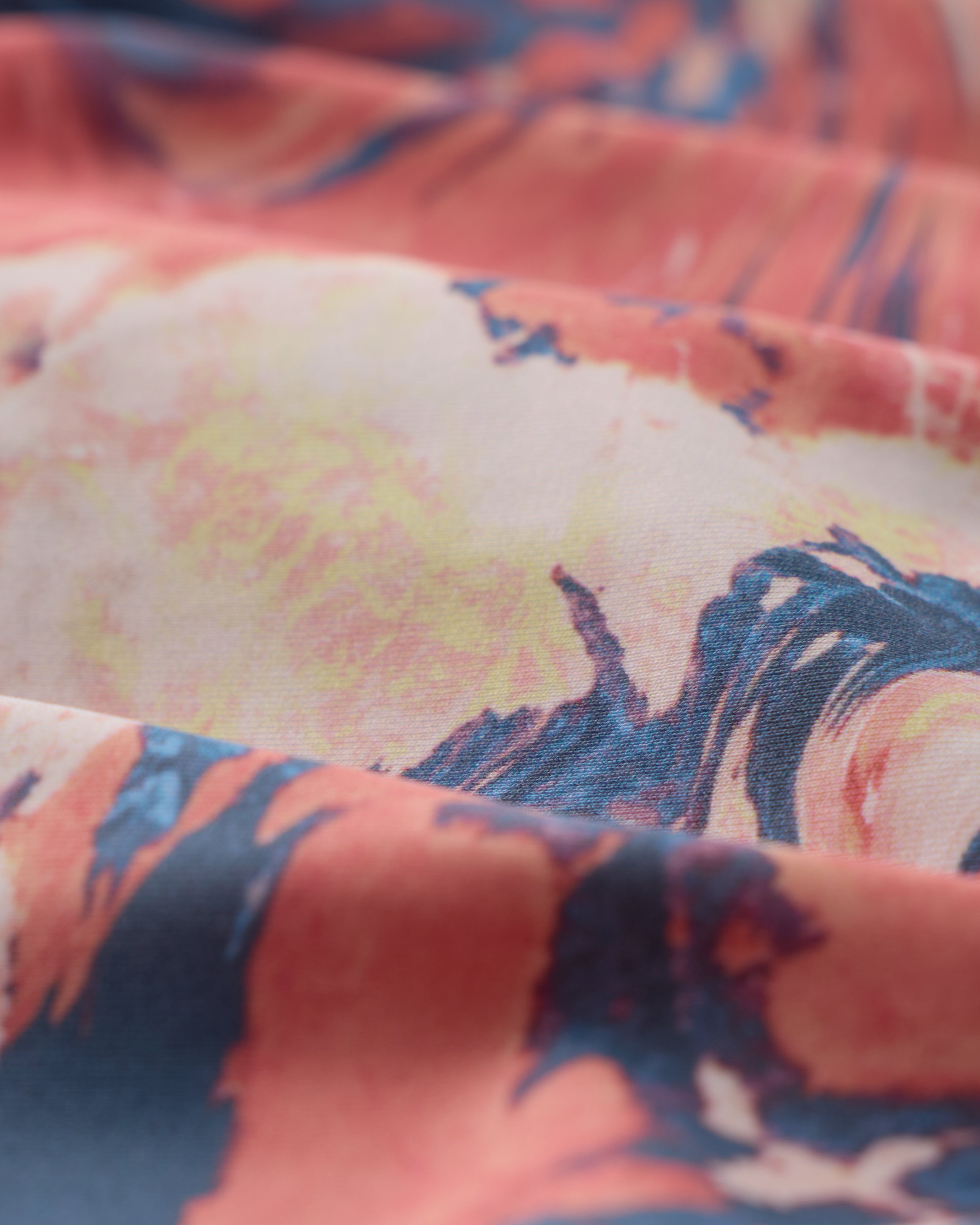 A close-up of The Avila Top - Lantana by Dandy Del Mar, made from recycled nylon and featuring a vibrant abstract pattern in coral, yellow, and navy blue.