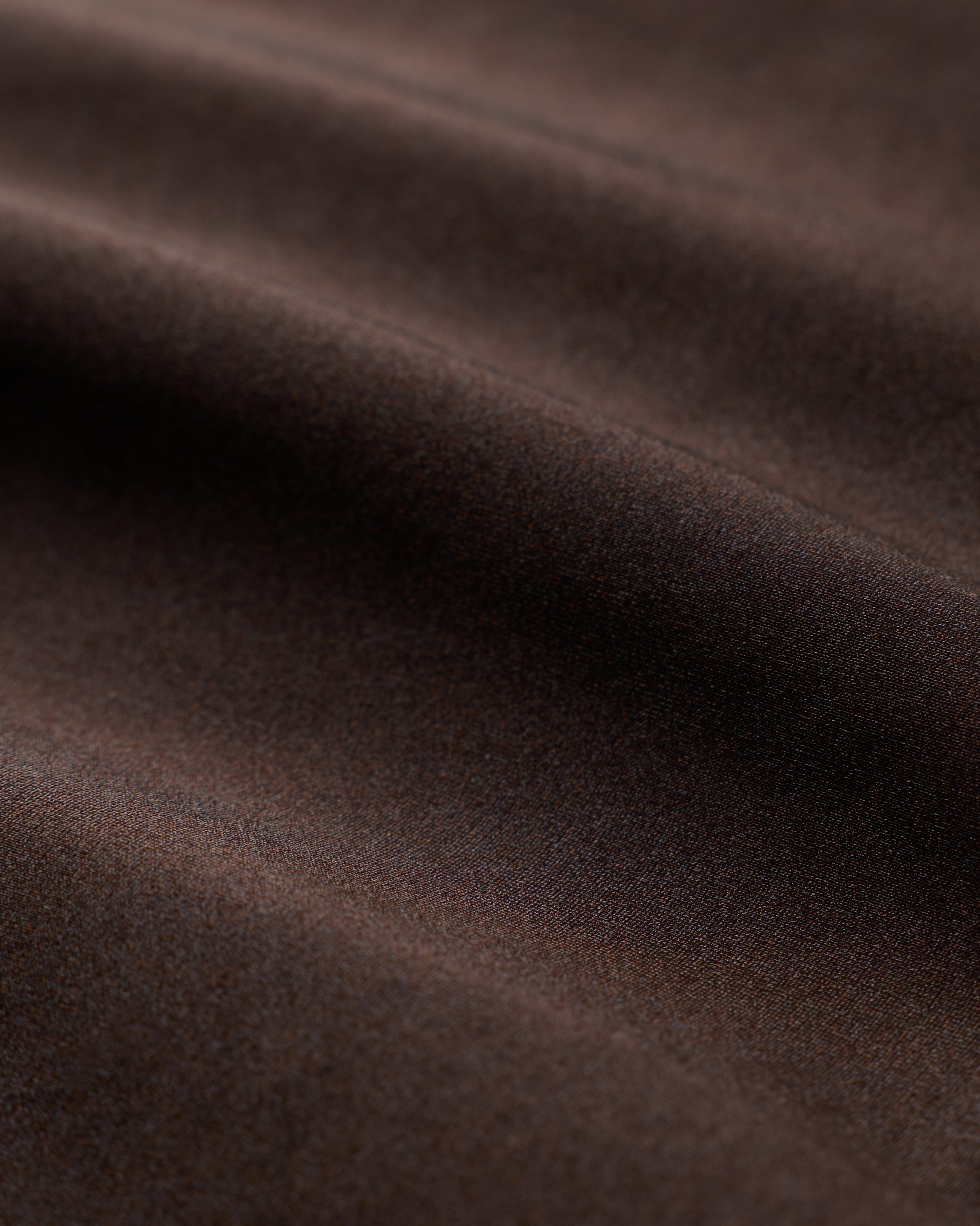 Close-up of the smooth brown fabric from The Elba One Piece - Tierra by Dandy Del Mar, featuring gentle folds that echo the elegant strapless silhouette and moderate coverage of this luxurious swimsuit. Soft shadows highlight its rich texture.