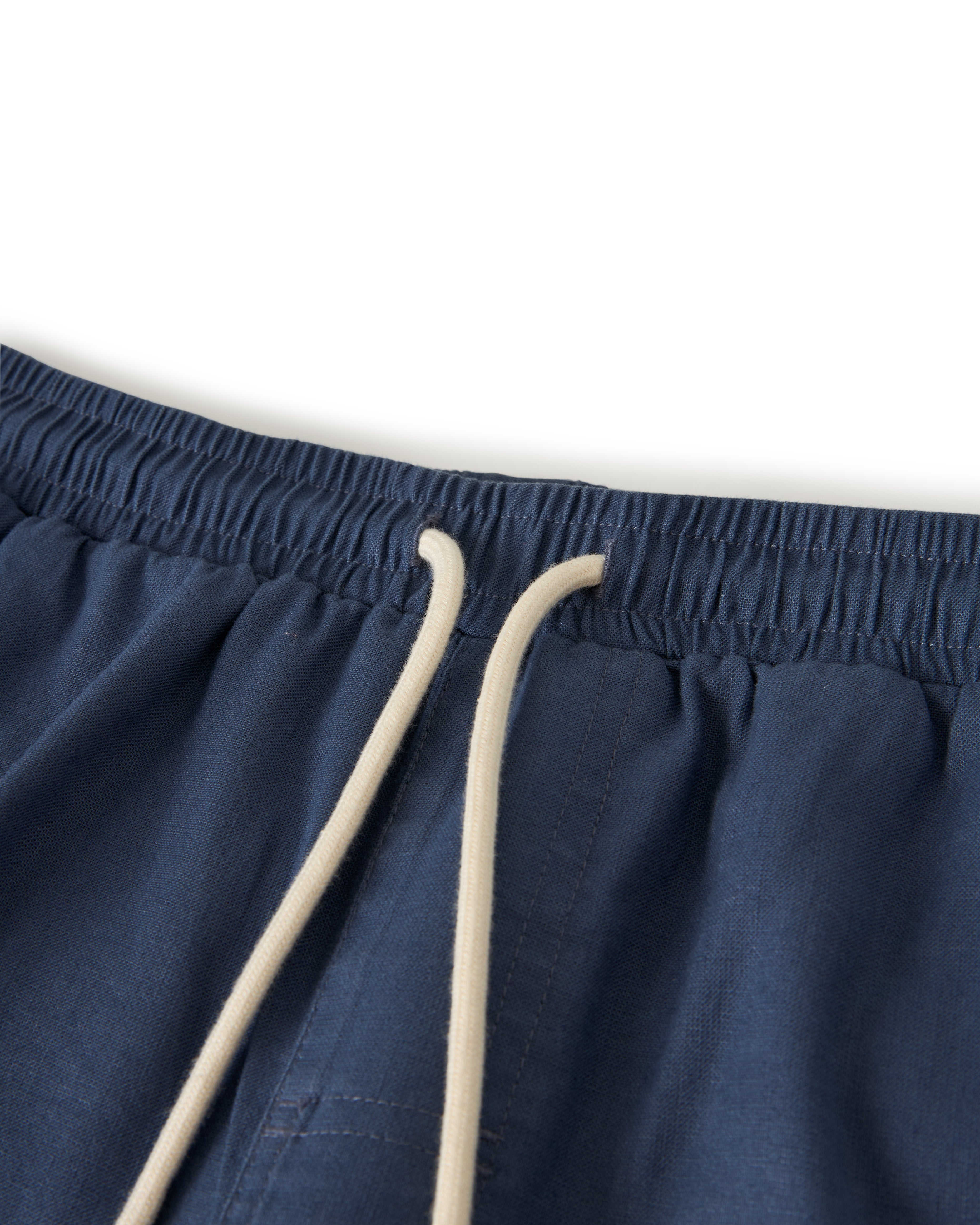 Close-up of The Brisa Linen Pant in Moontide by Dandy Del Mar, featuring a navy blue elastic waist and beige drawstring, perfect for vacation vibes.