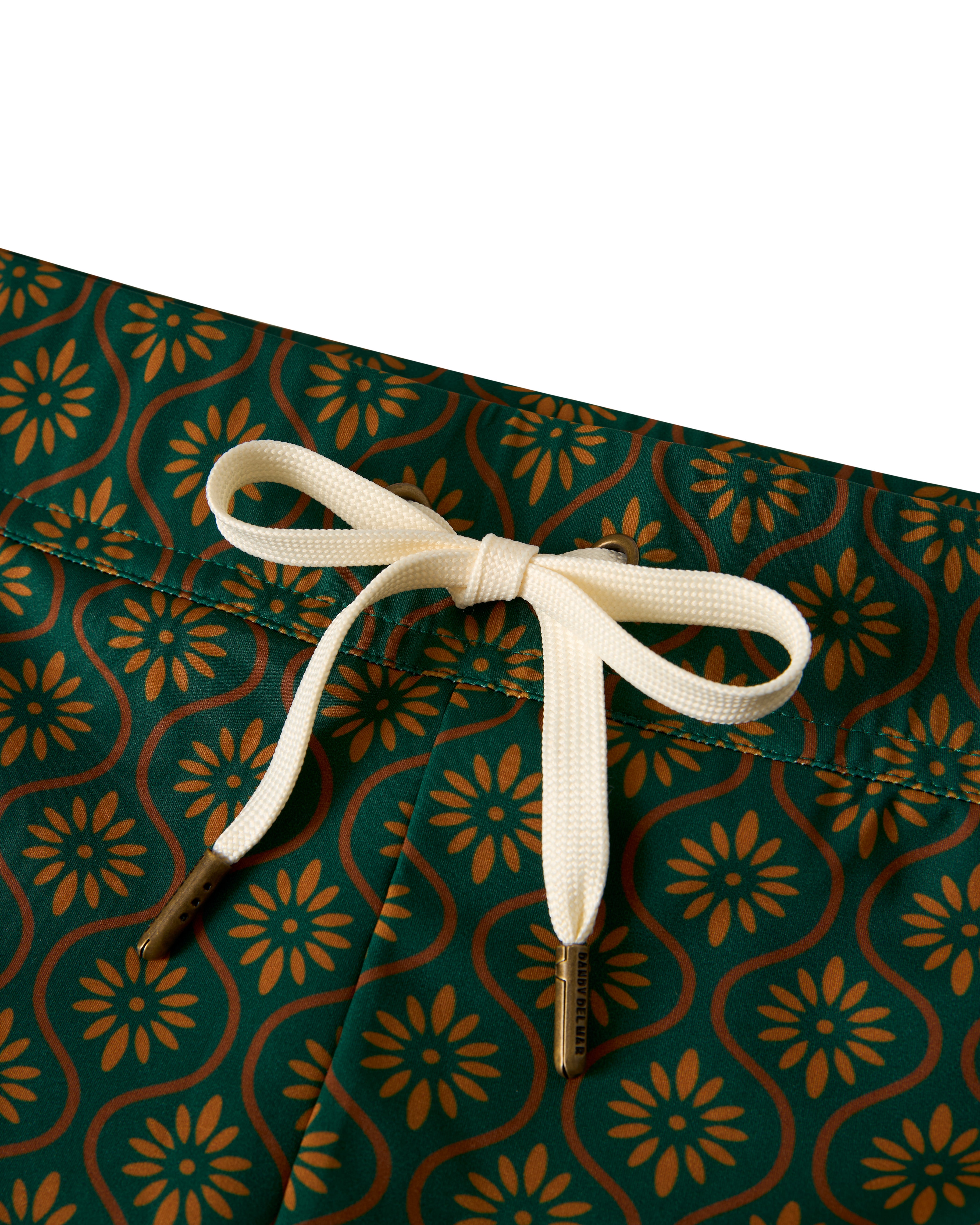 Close-up of The Cassis Square Cut Swim Brief - Albero by Dandy Del Mar, featuring green with an orange floral pattern and a white bow-tied drawstring, crafted from recycled polyester for eco-friendly style, offering a European fit that blends fashion with sustainability.