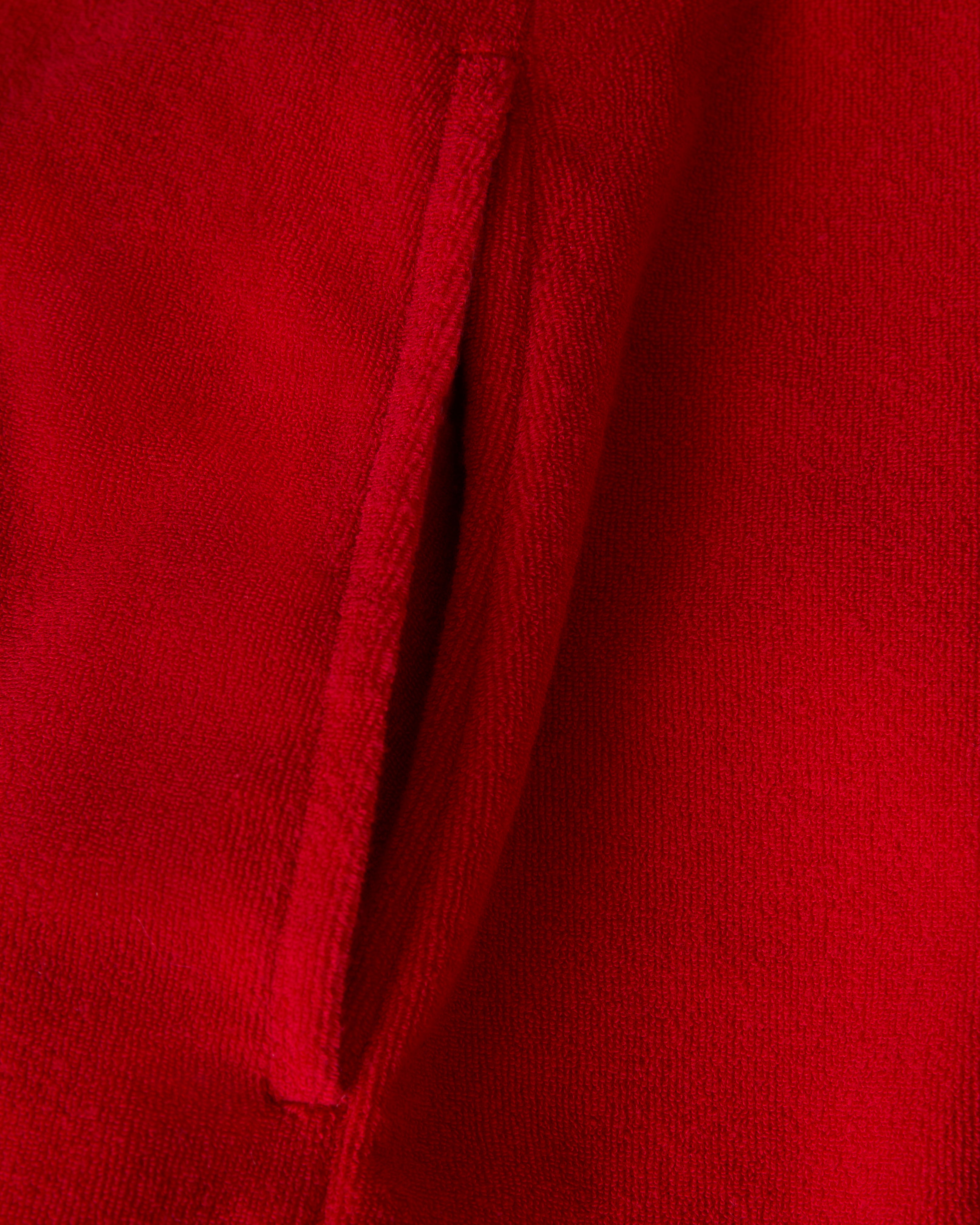 Close-up of The Cyprus Dress - Pico by Dandy Del Mar, featuring red terry cloth fabric and a vertical pocket opening on the left side.