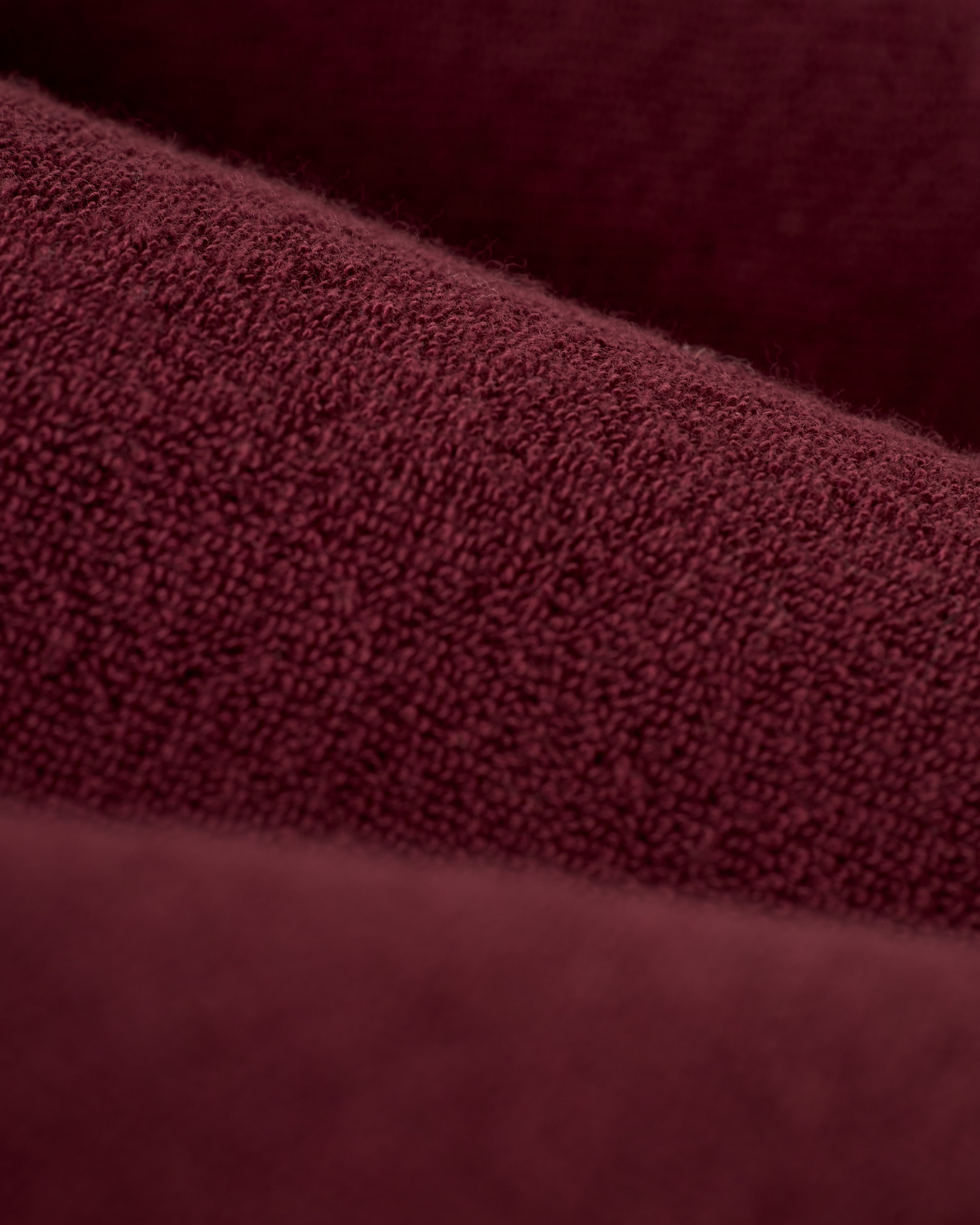 Close-up of The Gaucho Shirt in Bordeaux by Dandy Del Mar, showcasing a maroon terry cloth texture with soft horizontal folds that evoke an Equatorial Cowboy look.