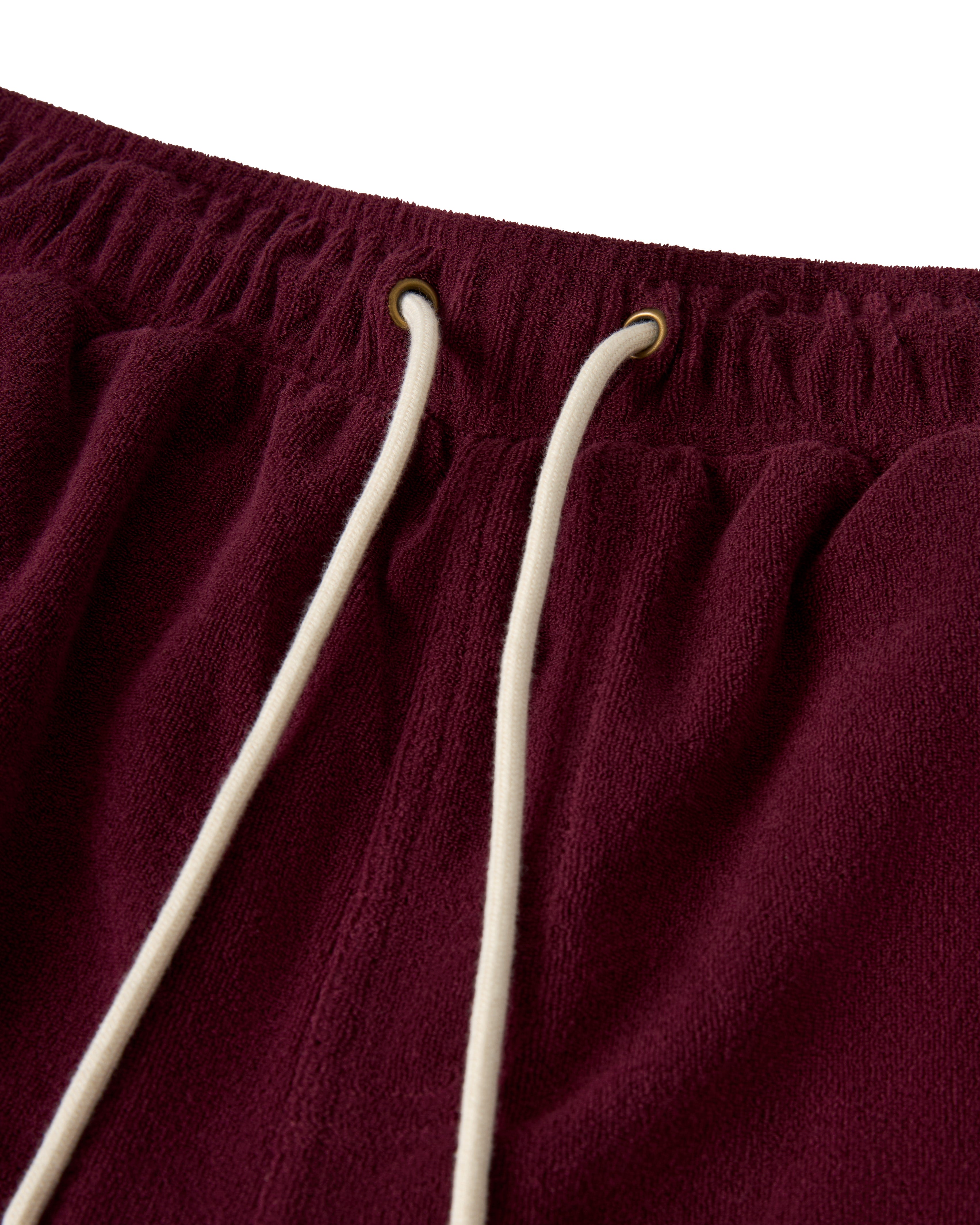 A close-up of The Gaucho Short - Bordeaux by Dandy Del Mar, featuring maroon fabric with white drawstrings through metal eyelets against a white background, exuding casual elegance akin to an Equatorial Cowboy.