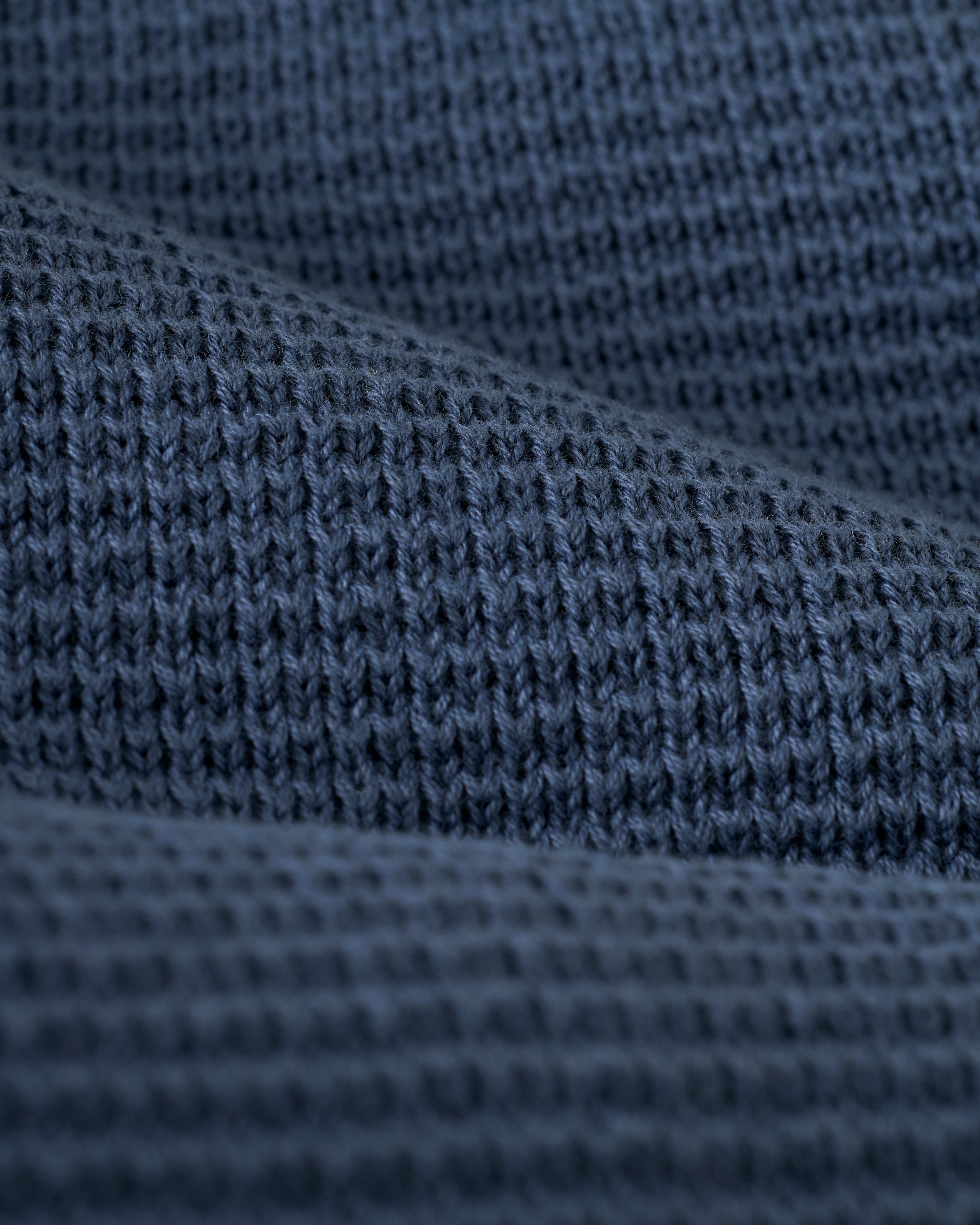 Close-up of the textured dark gray knit fabric from The Montego Knit Vest - Moontide by Dandy Del Mar, showcasing its visible stitching patterns.