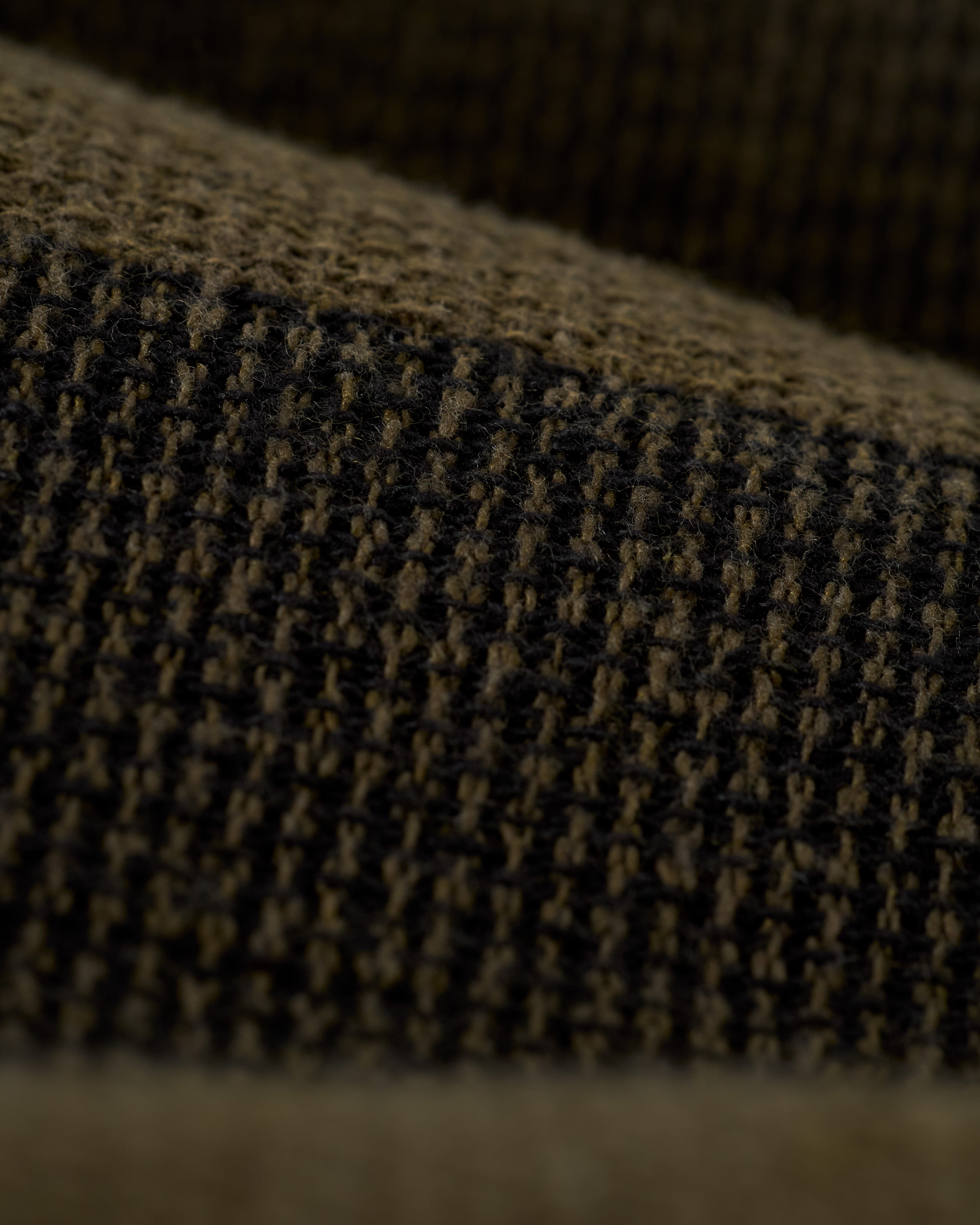 Close-up of The Palma Short - Onyx by Dandy Del Mar reveals its textured, dark brown fabric and grid-like pattern showcasing detailed fibers and woven structure.