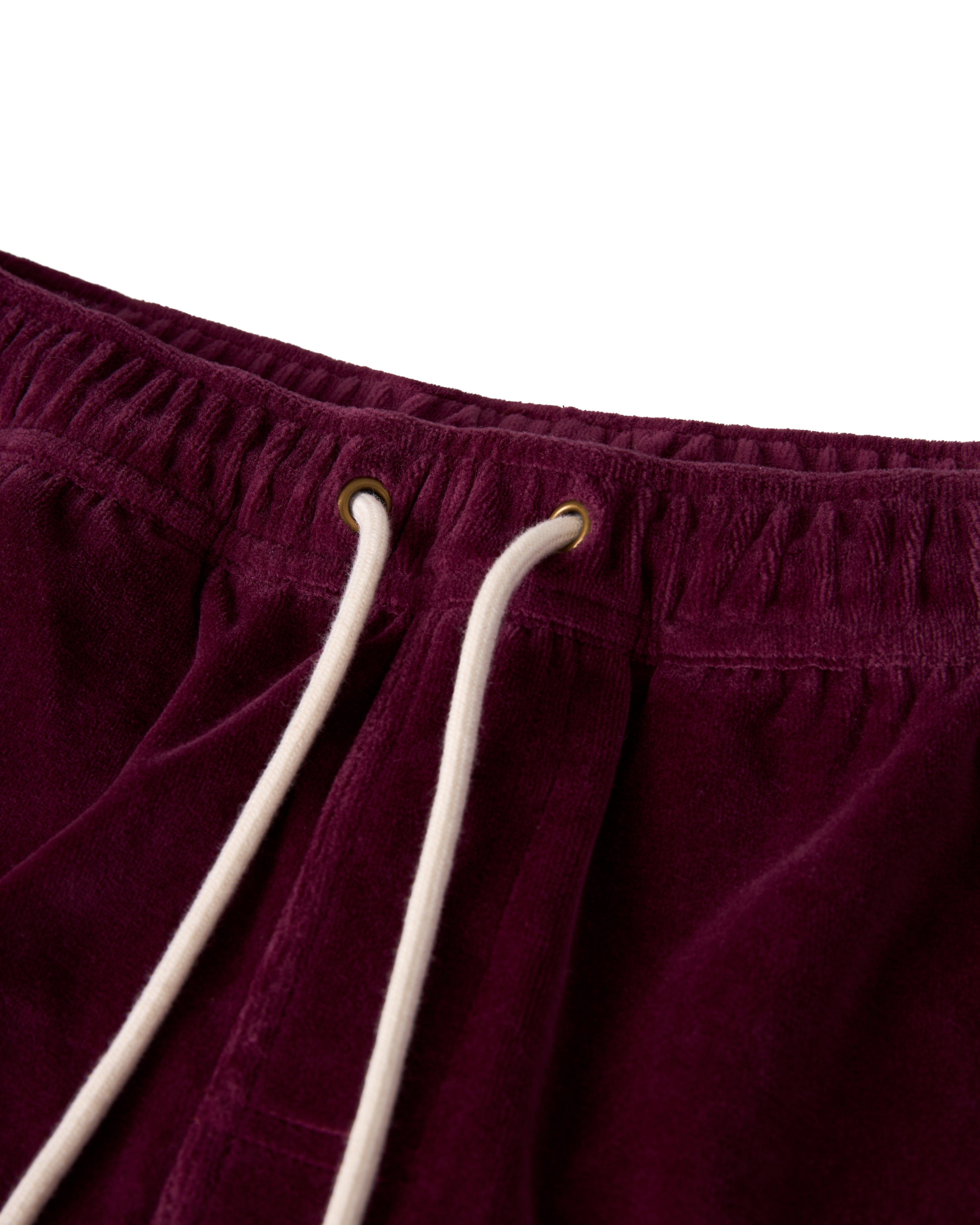 Close-up of The Rio Velour Short by Dandy Del Mar in Bordeaux, showcasing an elastic waistband with white drawstrings threaded through metal eyelets for a sporty look.
