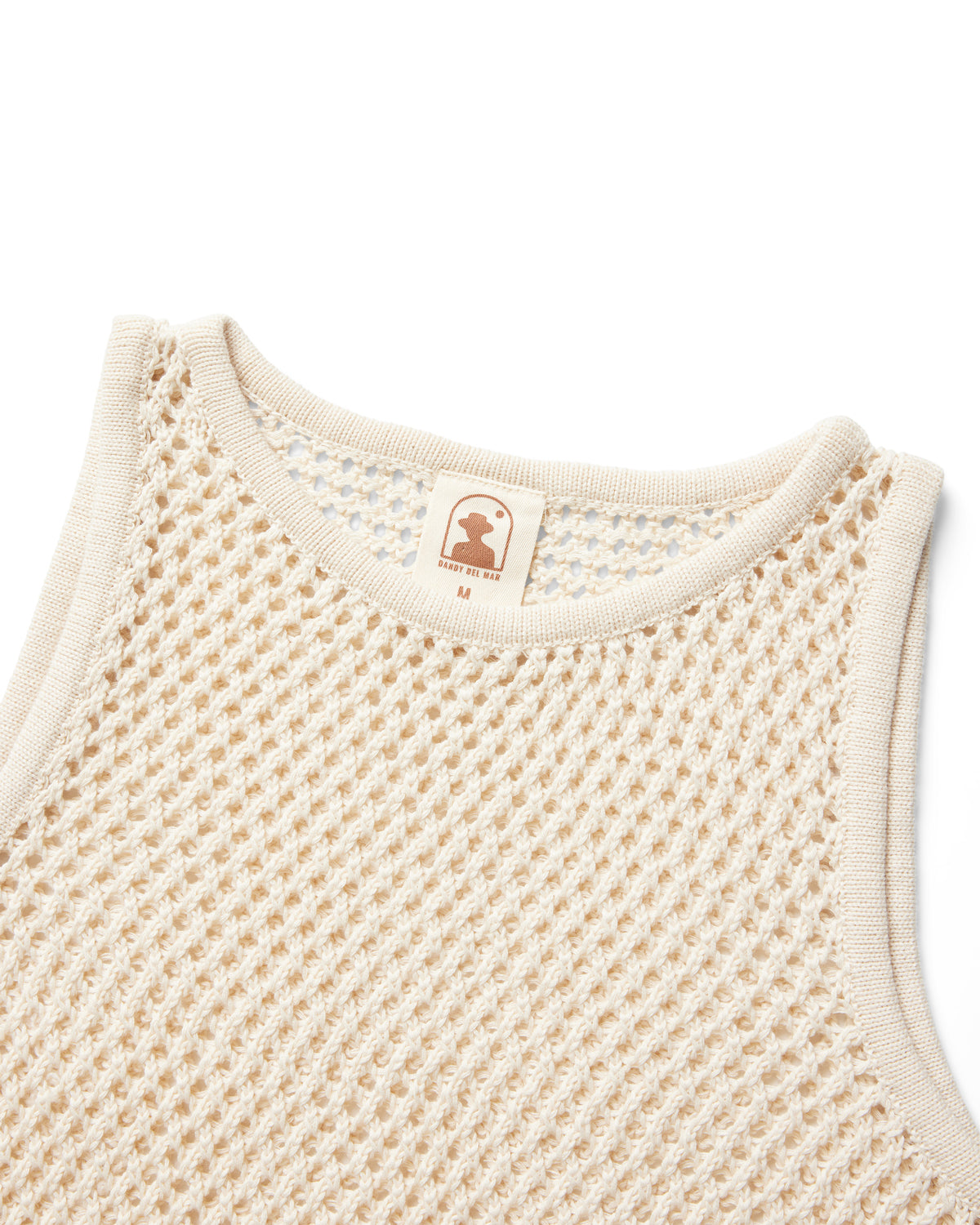Close-up of The Malaga Crochet Tank by Dandy Del Mar in Vintage Ivory—beige crochet knit with cream trim, sewn-in collar tag displaying a silhouette logo and size M. A relaxed fit summer top.