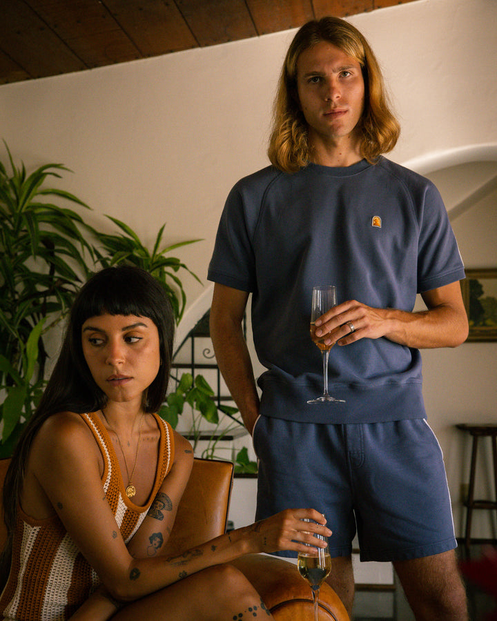 A man and woman standing next to each other in a living room wearing the Marseille Pullover by Moontide, from the brand Dandy Del Mar.