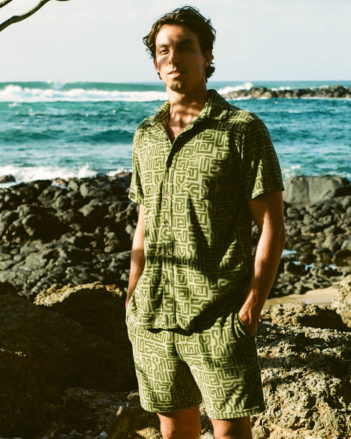 man in green terry cloth set on beach