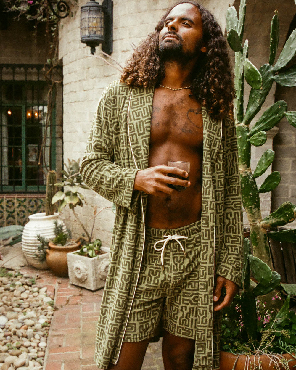 man outside in green robe with coffee