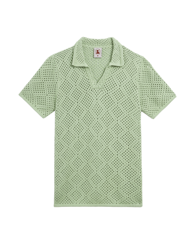 The Antibes Crochet Polo Shirt in Pistachio by Dandy Del Mar—a light green, short-sleeve collared shirt with a diamond-pattern knit and V-neck—displayed flat on a white background.