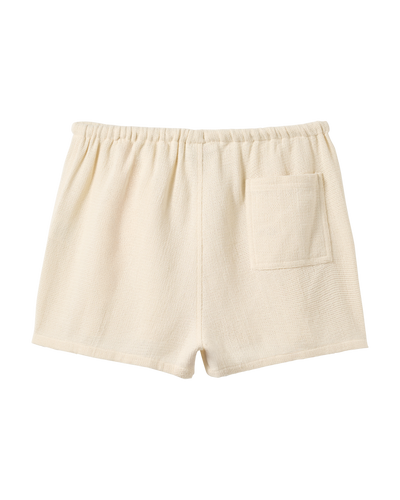 The Sevilla Shorts - Scallop by Dandy Del Mar feature cream terry cloth, an elastic waistband, and a back patch pocket. These mid-rise shorts are shown against a white background.