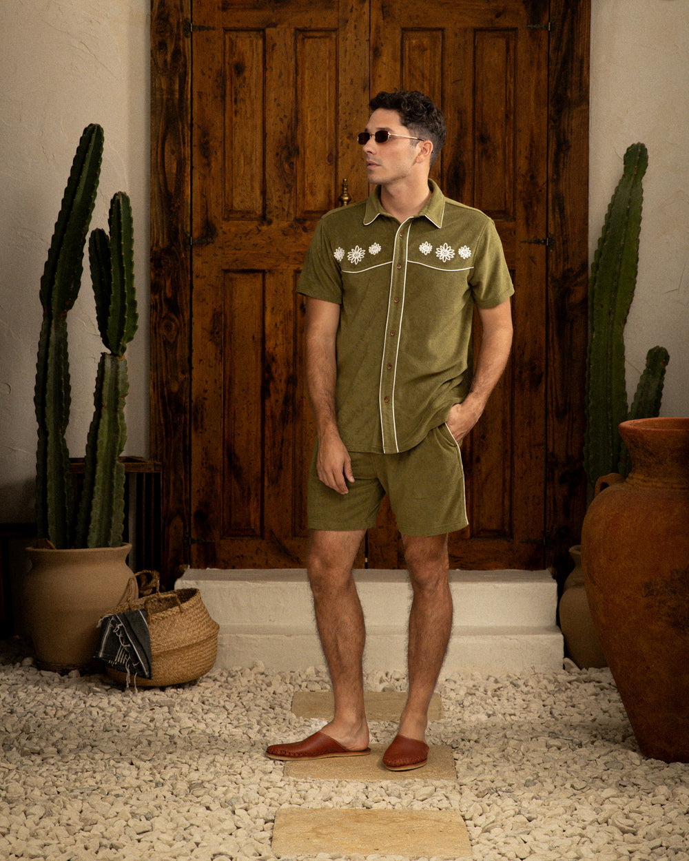 A man in a green Gaucho Short - Arbequina by Dandy Del Mar and shorts standing in front of a cactus.