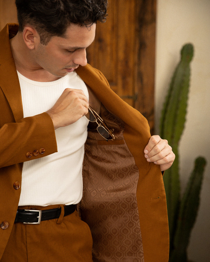 A man in a brown suit adjusting his pocket with The Brisa Linen Blazer - Sedona by Dandy Del Mar.