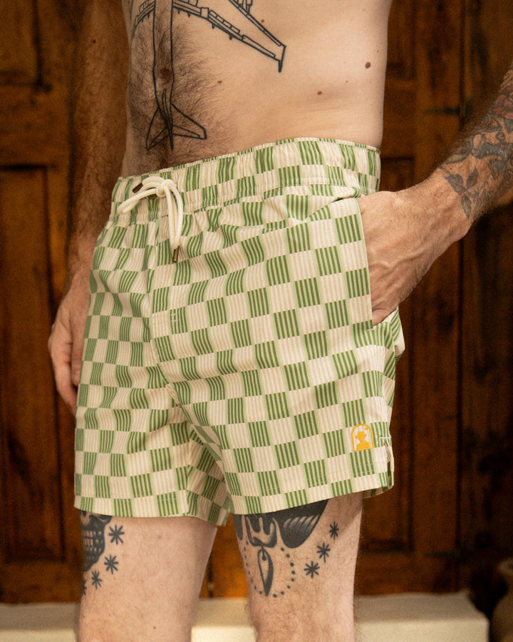 A man with tattoos wearing Dandy Del Mar Ventura Volley Shorts - Arbequina with an elastic waist.