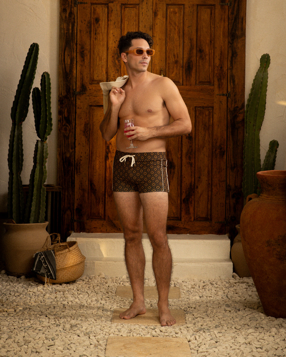 A man in The Cassis Square Cut Swim Brief - Cacao by Dandy Del Mar standing next to a cactus.