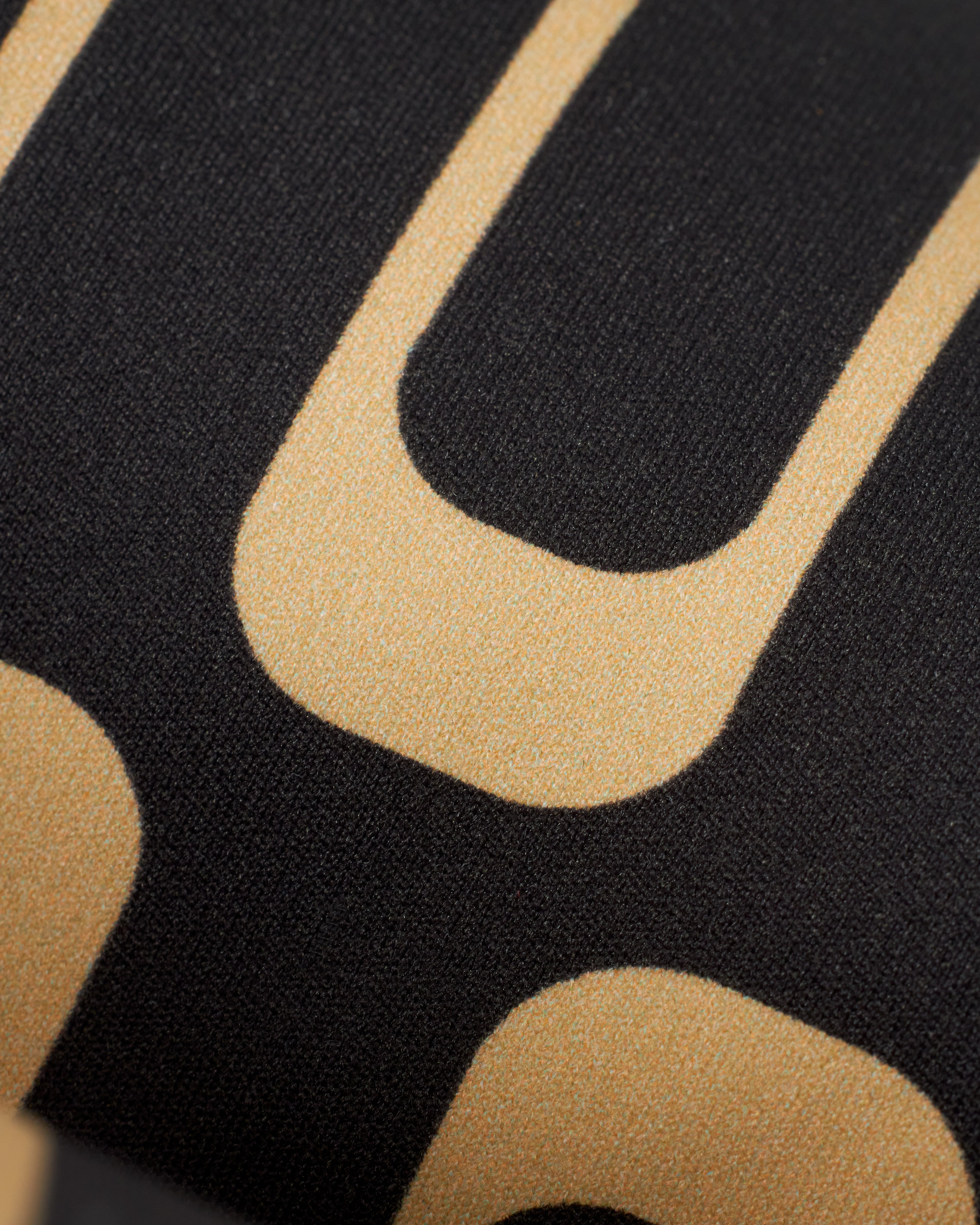 Close-up image of black fabric with large, beige, rectangular and curved designs, perfect for The Gomera Bottom - Albatross by Dandy Del Mar.