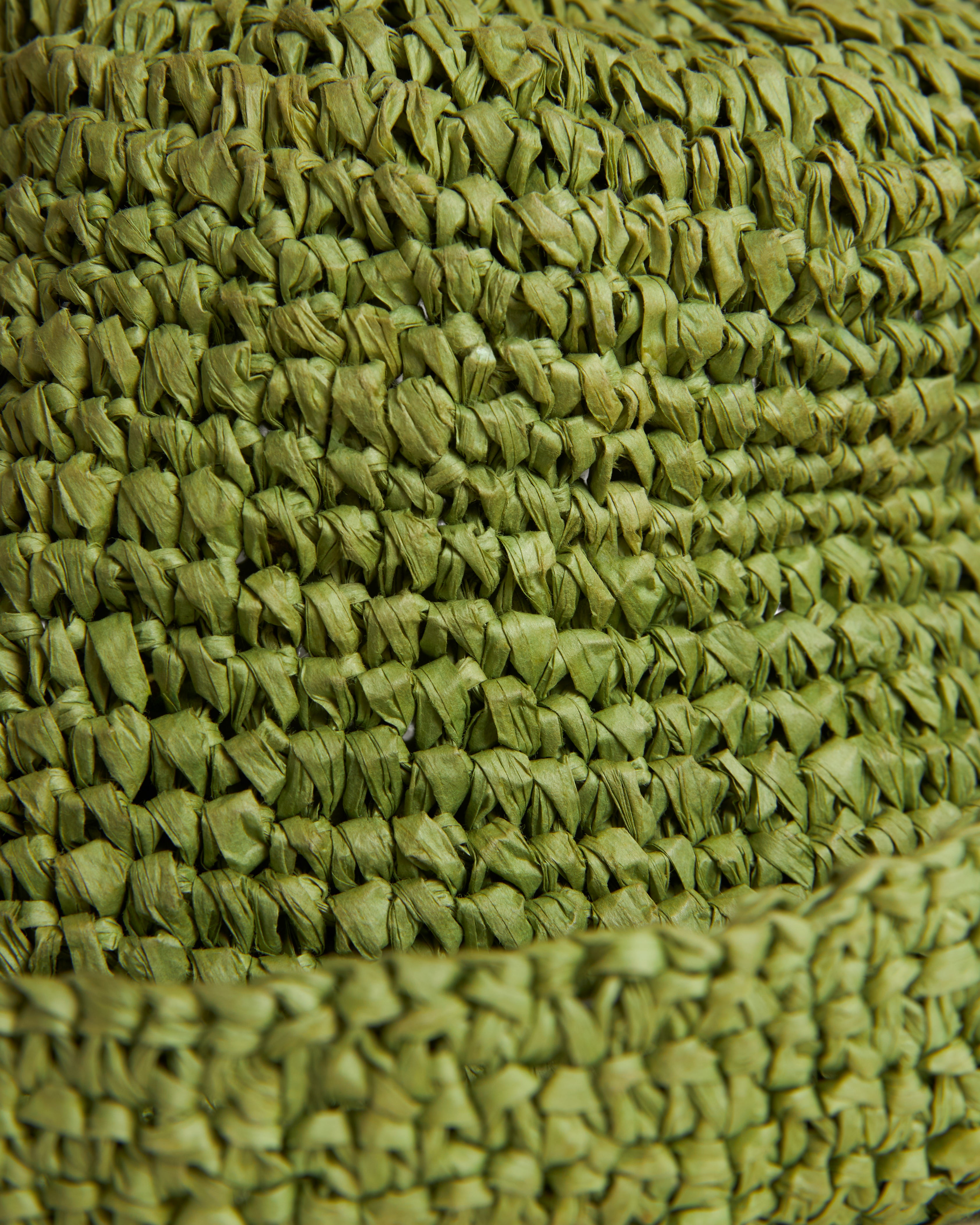 Close-up of The Amabile Raffia Hat - Verde by Dandy Del Mar, showcasing its tightly interlaced green woven texture, reminiscent of raffia-effect crochet.