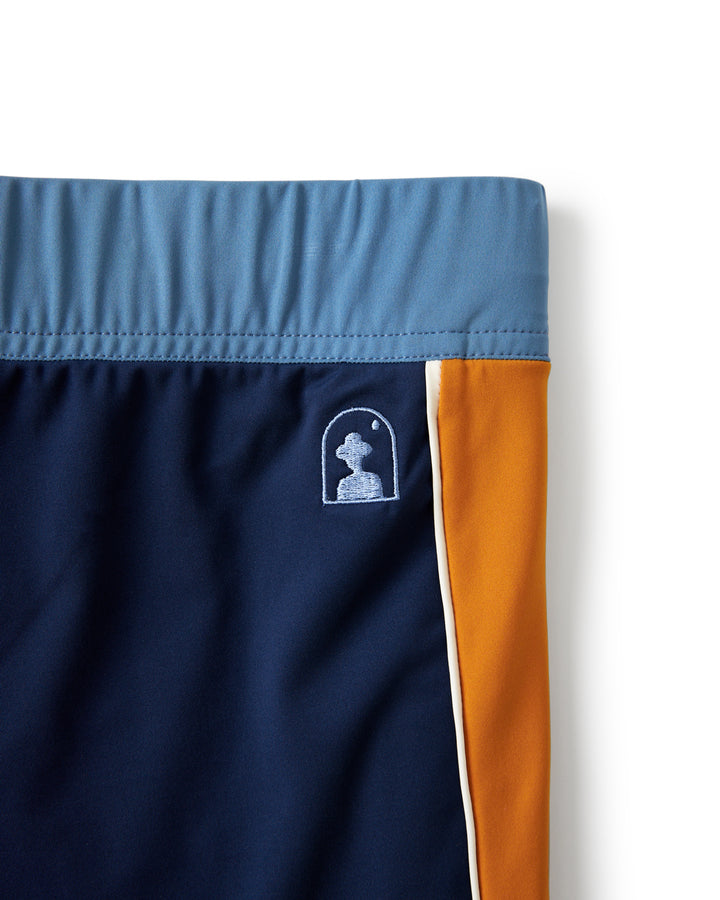 A pair of Dandy Del Mar leisure swim trunks with a European fit and the "Cassis Square Cut Swim Brief - Anchor" logo in orange and blue.