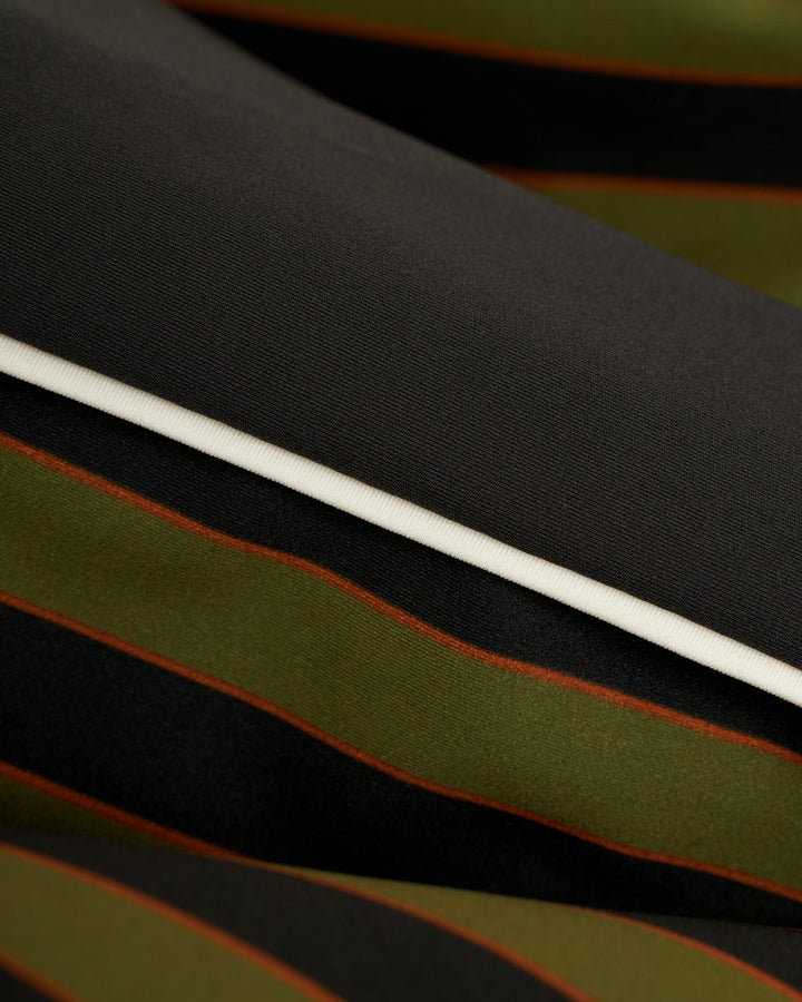 A close up of a Dandy Del Mar Cassis Square Cut Swim Brief - Arbequina, showcasing its black and green striped fabric.
