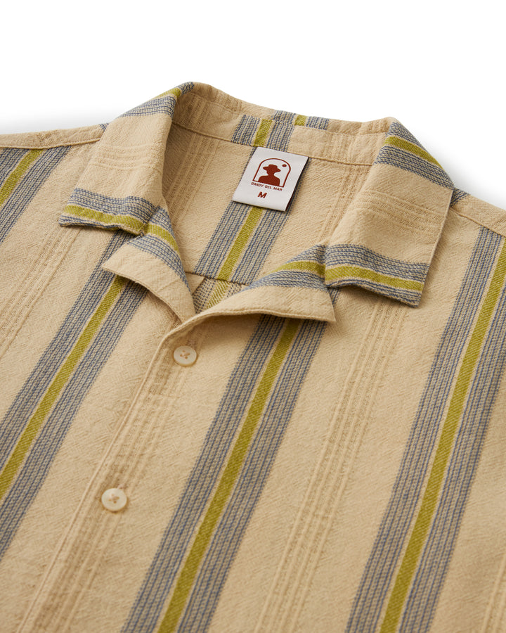 A beige Dandy Del Mar Corralejo Shirt with a yellow and green stripe, made from textured gauze fabric and adorned with abalone shell buttons.