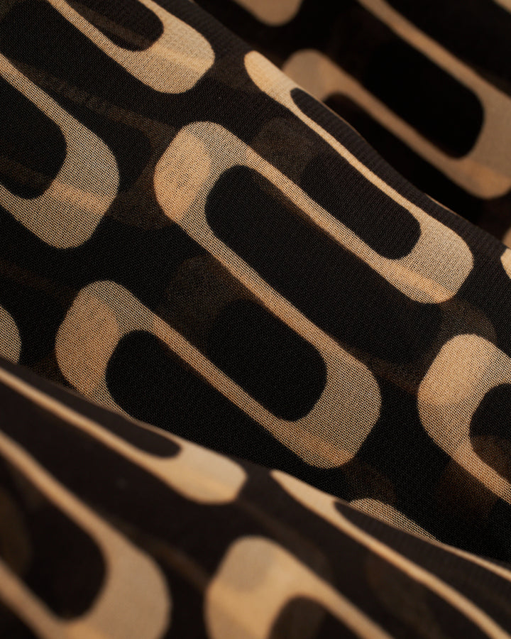 A close up of The Curacao Chiffon Dress - Albatross by Dandy Del Mar, a black and beige fabric.
