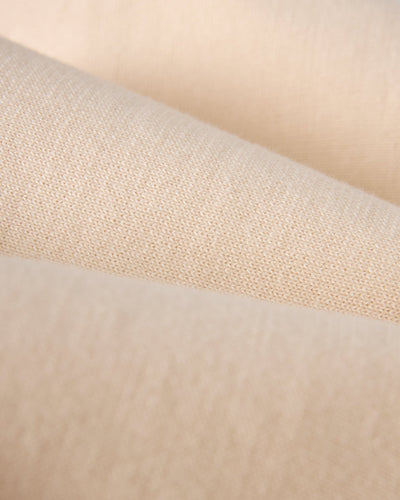 Close-up of beige, textured lightweight cotton fabric with visible weave and smooth finish—ideal for a vintage-sport vibe, as seen in the Dandy Del Mar Grenada Knit Baseball Tee - Tierra.