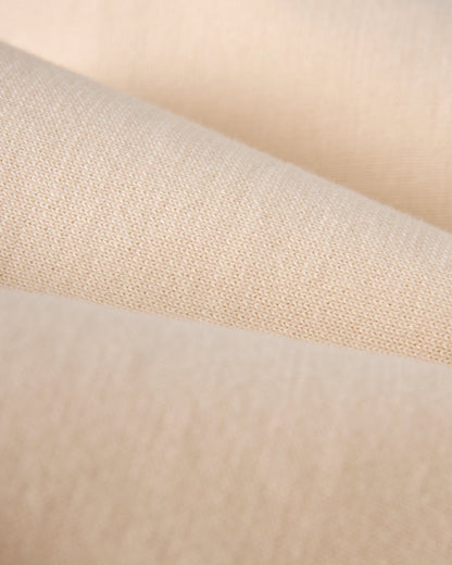 Close-up of The Grenada Sweater Knit Baseball Tee - Tierra by Dandy Del Mar, featuring beige lightweight cotton fabric with a soft texture and visible weave pattern, inspired by vintage-sport style.