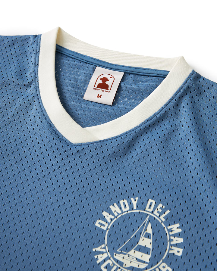A blue Kaena Mesh Tee - Annapolis by Dandy Del Mar with an image of a sailboat on it.
