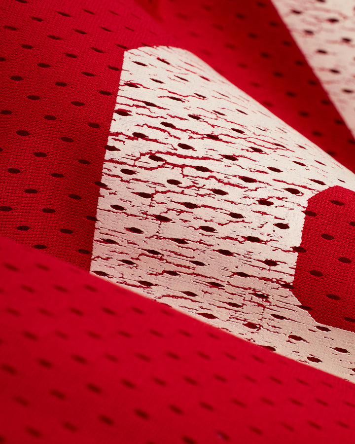 A close up of a red and white Dandy Del Mar Kaena Mesh Tee basketball jersey.