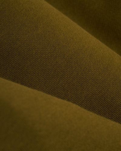 Close-up of olive green fabric with a visible weave, softly folded—perfect for Dandy Del Mar’s The Marseille French Terry Shorts in Arbequina.