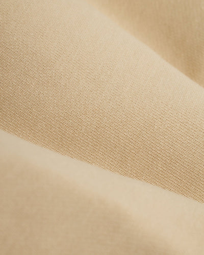 Close-up of The Marseille French Terry Shorts - Ginger by Dandy Del Mar, featuring smooth beige fabric with a visible weave in soft folds—perfect for crafting comfortable, stylish shorts.