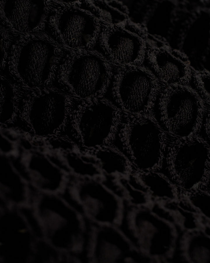 A close up of the Montserrat Skirt - Onyx by Dandy Del Mar, a black knitted fabric.