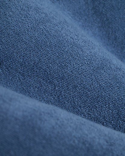 Close-up of the ultra-soft blue fabric of The Tropez Robe - Annapolis by Dandy Del Mar, featuring parallel wavy folds reminiscent of cozy terry cloth.