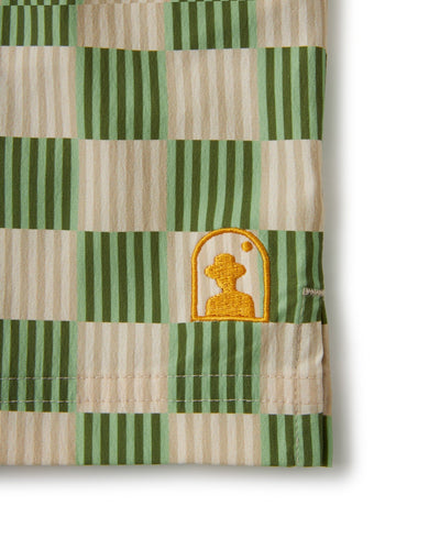 Close-up of The Ventura Volley Shorts - Arbequina by Dandy Del Mar, crafted from green and beige checkered fabric with yellow pawn chess piece embroidery inside an arch, showcasing the stylish details and elastic waistband.