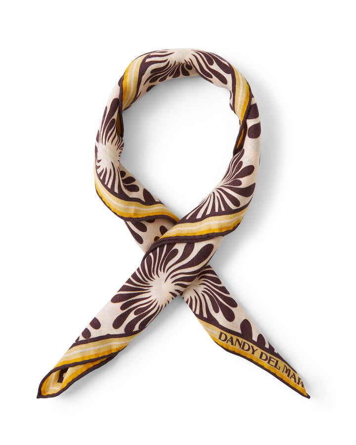 A brown and yellow Amalfi Woven Ascot - Carajillo Fleur scarf from Dandy Del Mar with a floral pattern.