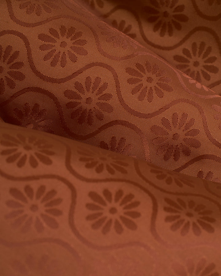 A close up of The Brisa Linen Blazer - Onyx by Dandy Del Mar, a brown fabric with a floral pattern showcasing fine linens.