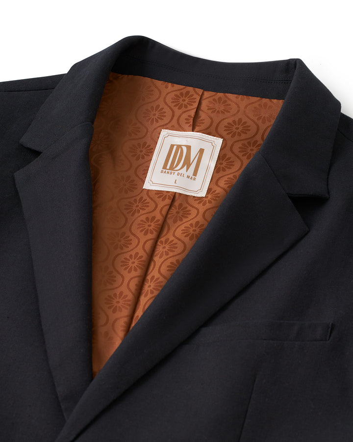 A silk-lined Dandy Del Mar Brisa Linen Blazer - Onyx with a flirtatious orange label.