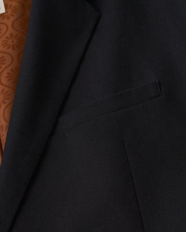 A close up of the Dandy Del Mar Brisa Linen Blazer - Onyx with a brown pocket.