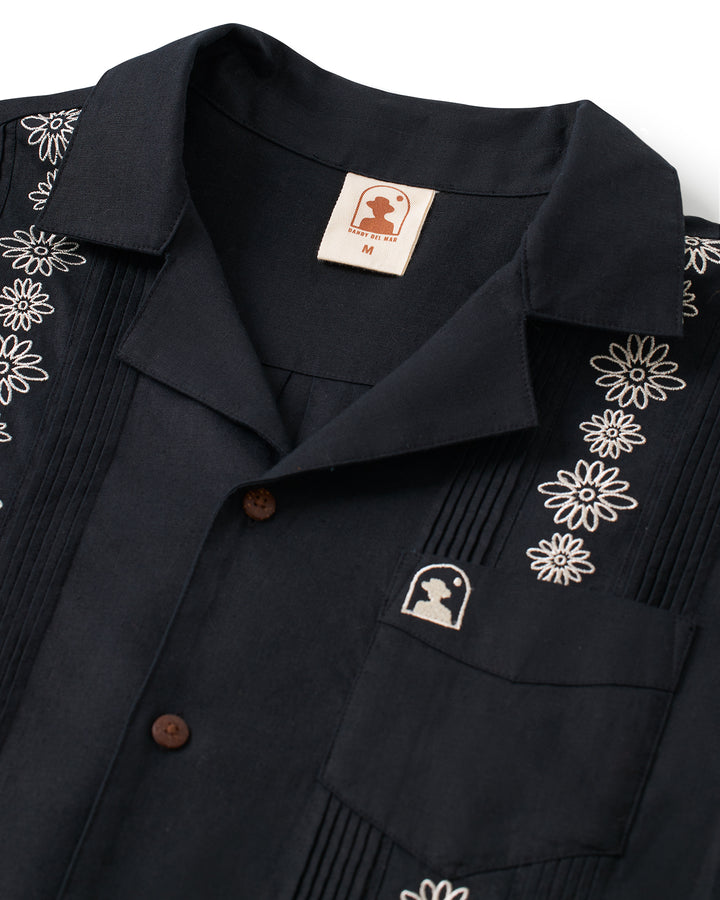 A black Dandy Del Mar Brisa Linen Shirt - Onyx with signature gardenia floral embroidery.
