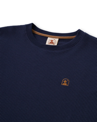 Close-up of Dandy Del Mar's Cannes LS Waffle Knit Shirt in Luxe Navy, featuring a textured waffle knit, small brown embroidered chest logo patch, and a branded collar tag.