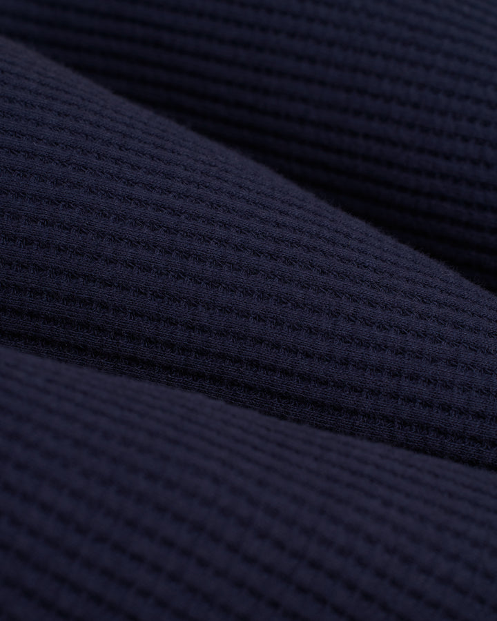 A close up of the Dandy Del Mar Cannes Robe - Luxe Navy, a dark blue knit fabric.