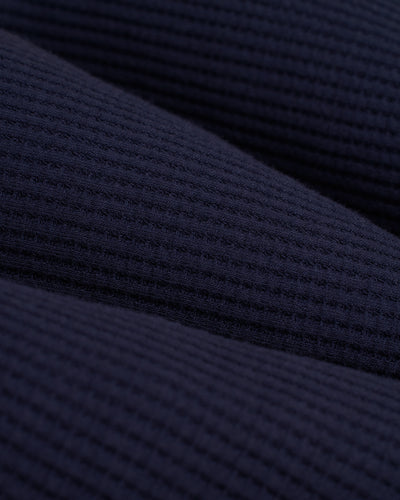Close-up of the Luxe Navy Cannes LS Waffle Knit Shirt by Dandy Del Mar, showcasing its dark blue, ribbed texture with parallel lines and a grid-like waffle knit pattern.