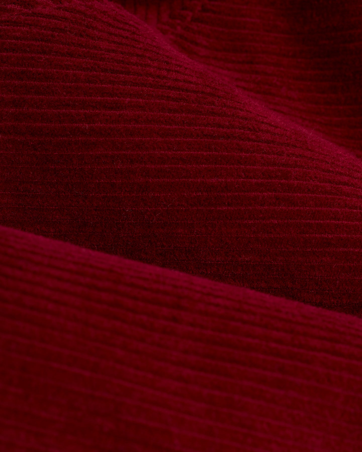 Close-up view of Italian corduroy fabric, showcased in the Dandy Del Mar Corsica Corduroy Jacket - Sangria, highlighting its rich, textured, ribbed surface.